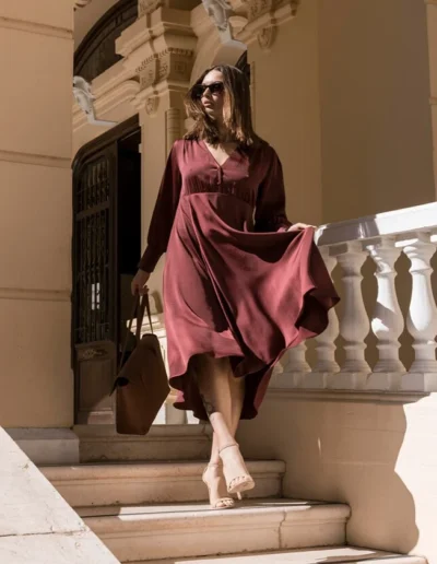 Elegant woman in a flowing maroon midi dress, showcasing luxury apparel manufacturing