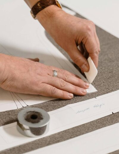 Hands marking biodegradable fabric with pattern paper for eco-friendly clothing production at Ibex Fashion.